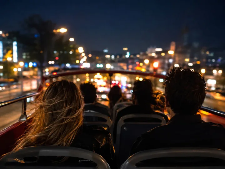 Passengers on an open-top bus deck at night