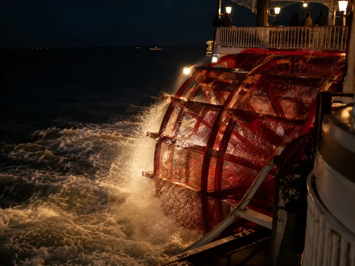 A paddle wheel churning dark water at night