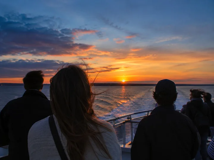Passengers on an upper deck at dusk