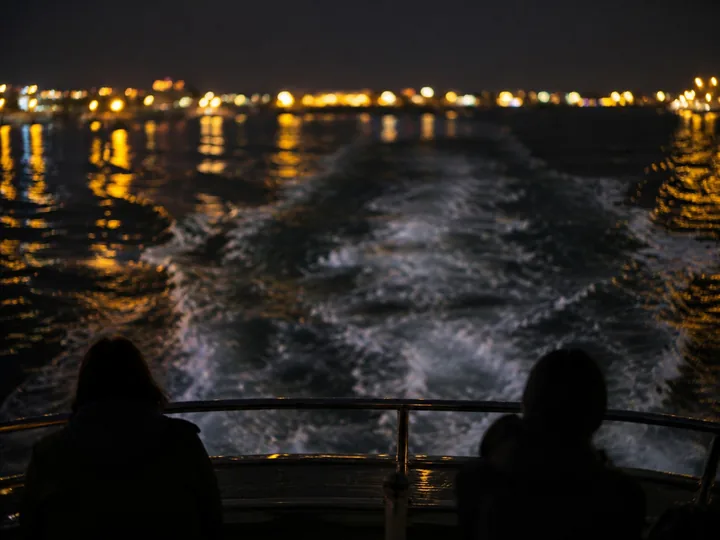 A boat wake reflecting city lights at night