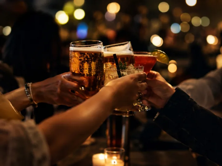 Hands clinking glasses of beer in a bar