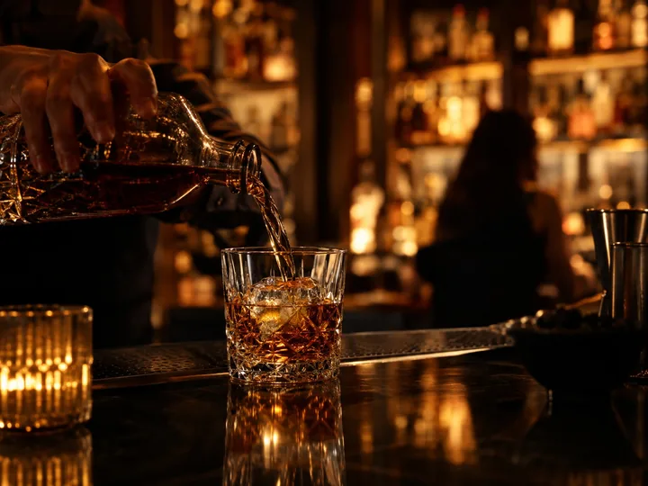 A bartender pouring whiskey into a glass