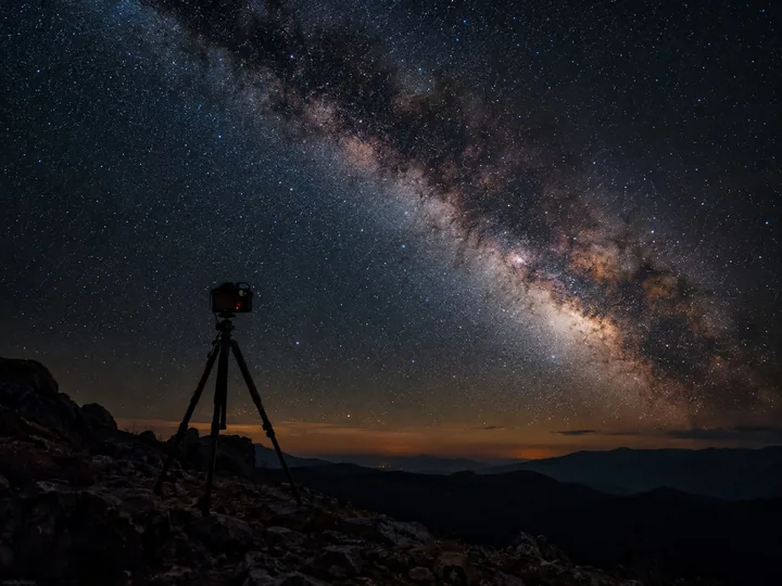 A camera on a tripod pointed at the Milky Way