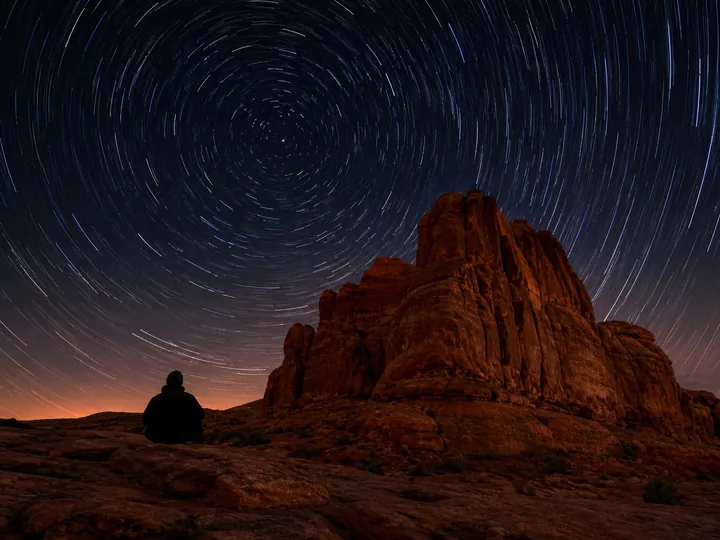 Star trails over a red rock formation