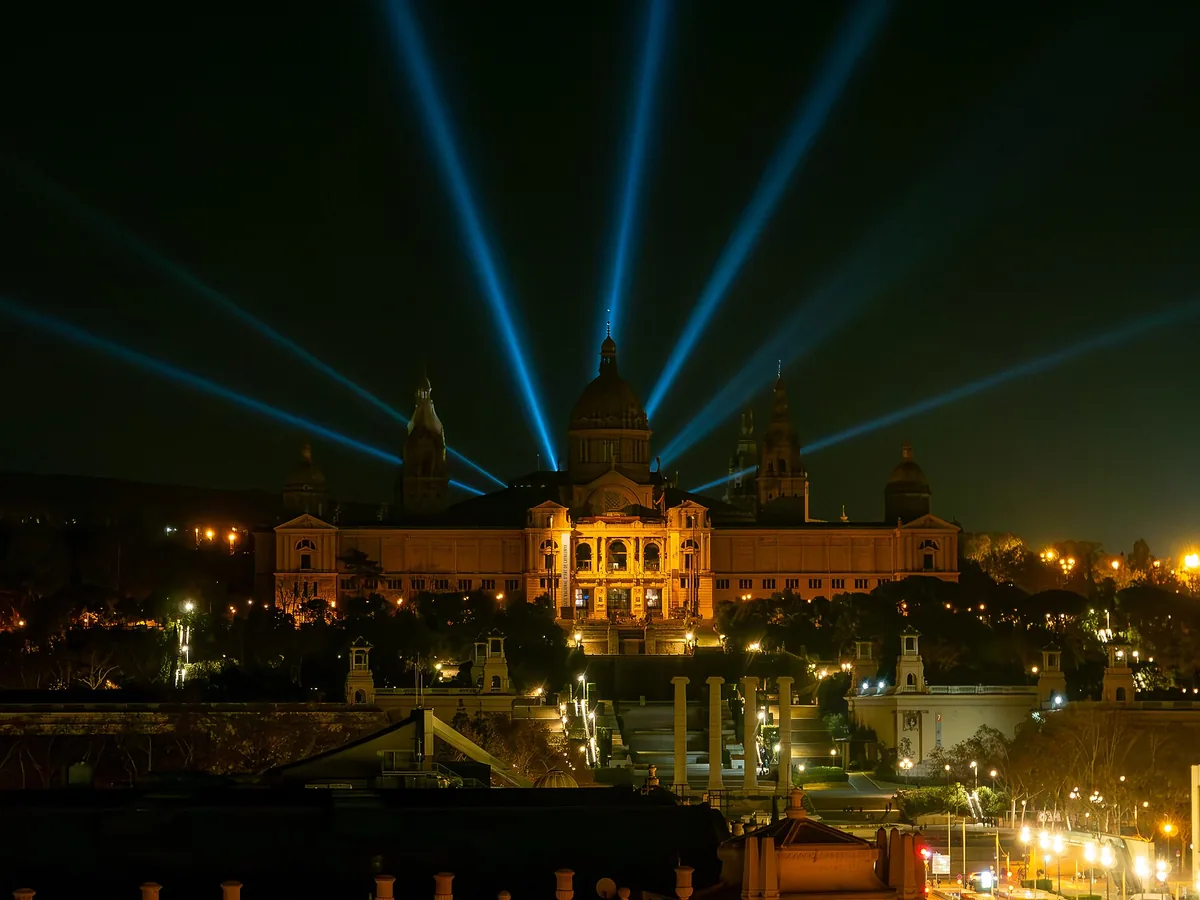 The Palau Nacional on Montjuïc in Barcelona lit at night, with searchlight beams above it