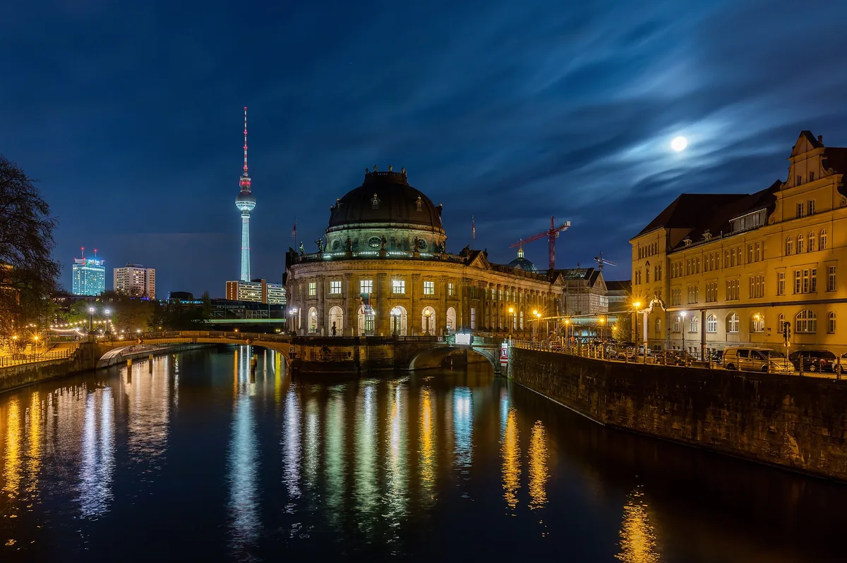 The Bode Museum and the TV tower over the Spree in Berlin at night, with the moon behind cloud