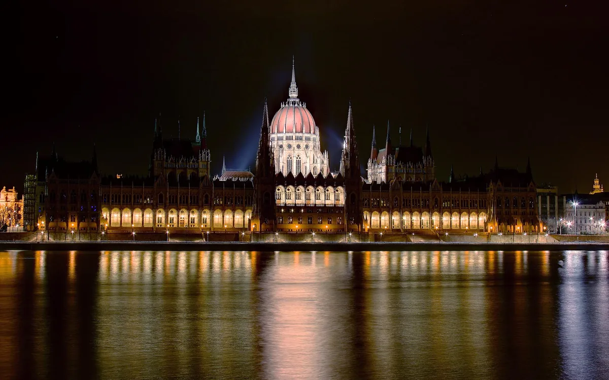 The Hungarian Parliament in Budapest lit up at night and reflected in the Danube