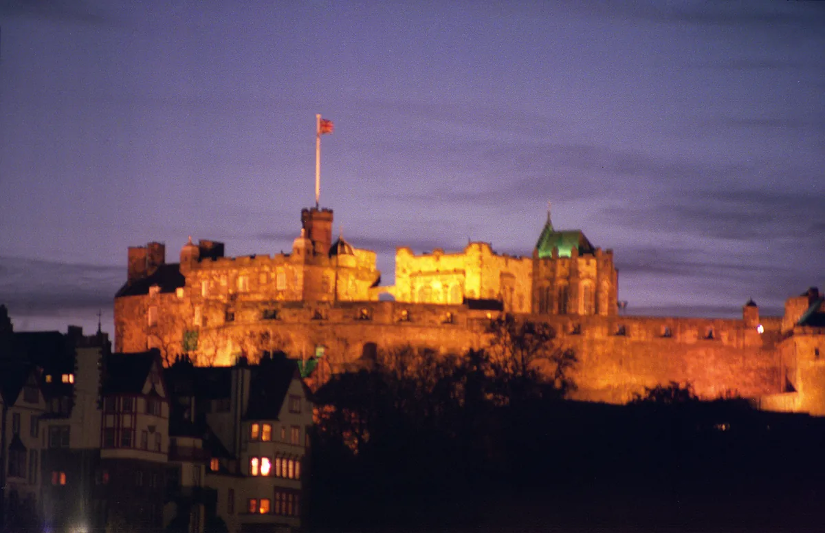 Edinburgh Castle floodlit orange on its rock above the city at night