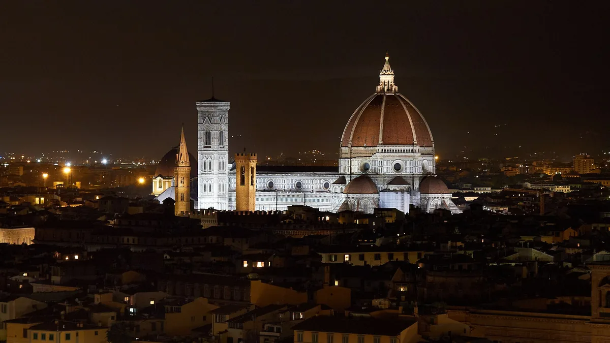 Florence Cathedral's dome and Giotto's bell tower lit above the rooftops at night