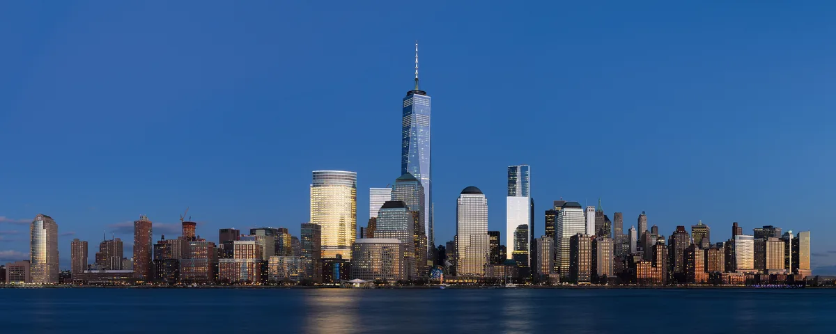 The Lower Manhattan skyline and One World Trade Center at blue hour across the Hudson