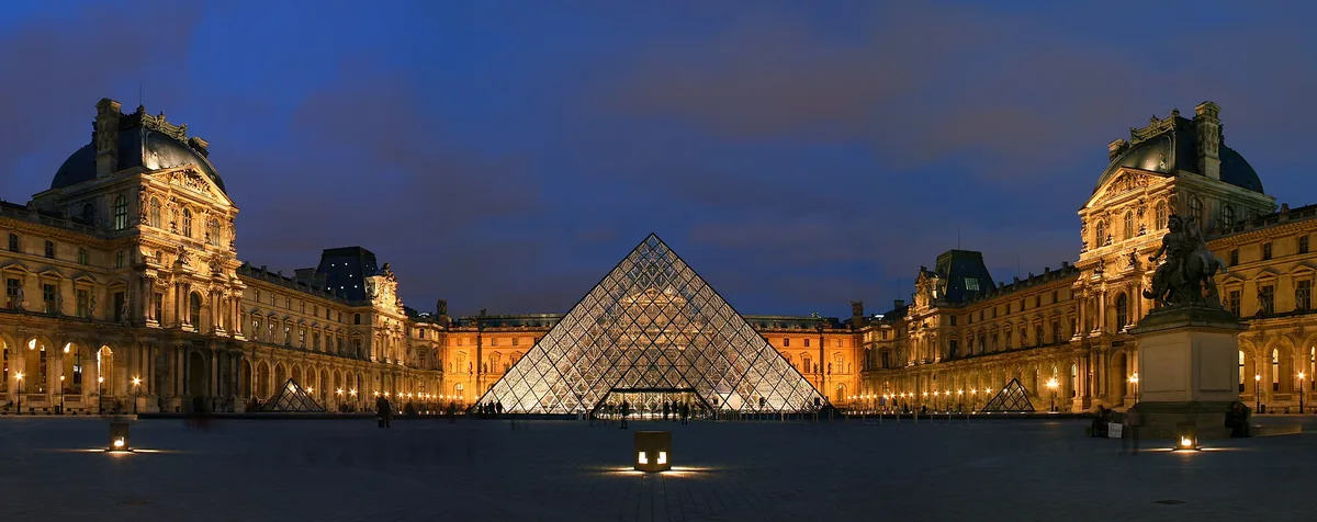 The Louvre courtyard and its glass pyramid lit at blue hour in Paris