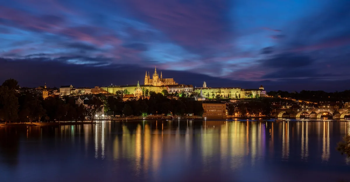 Prague Castle lit at night and reflected in the Vltava river
