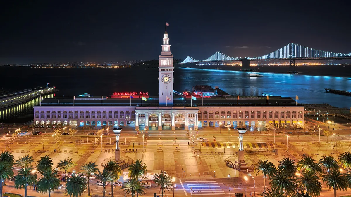 The Ferry Building in San Francisco at night, with the lit Bay Bridge behind