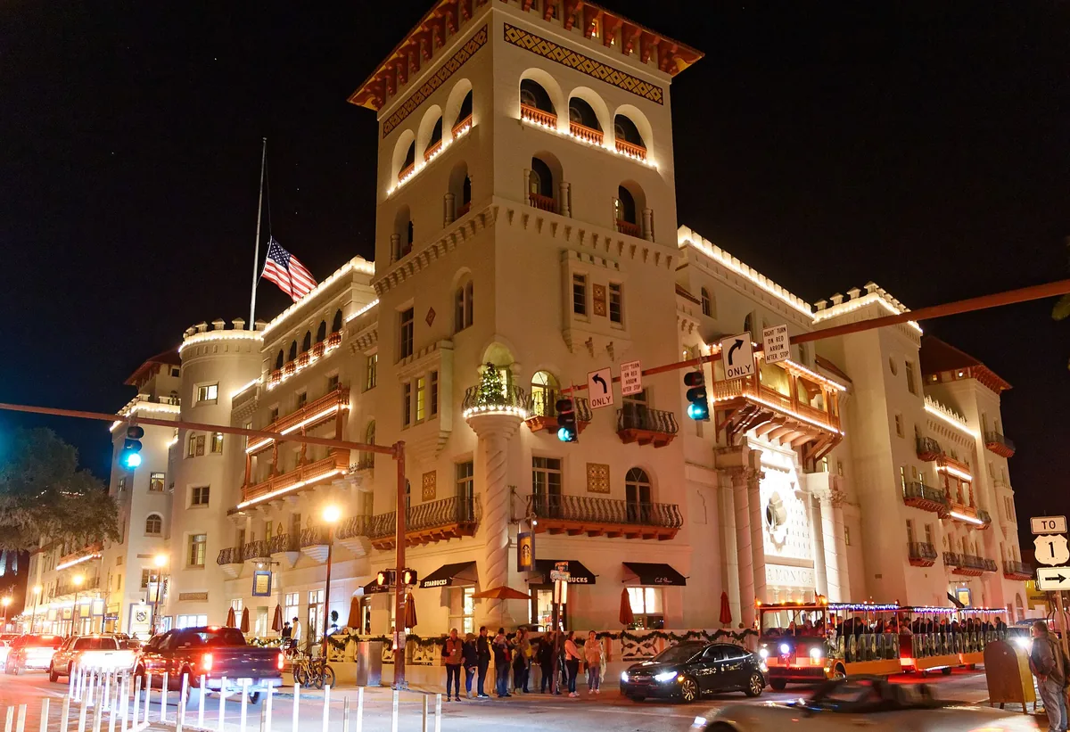 The Casa Monica Hotel in St. Augustine lit at night, with a trolley passing