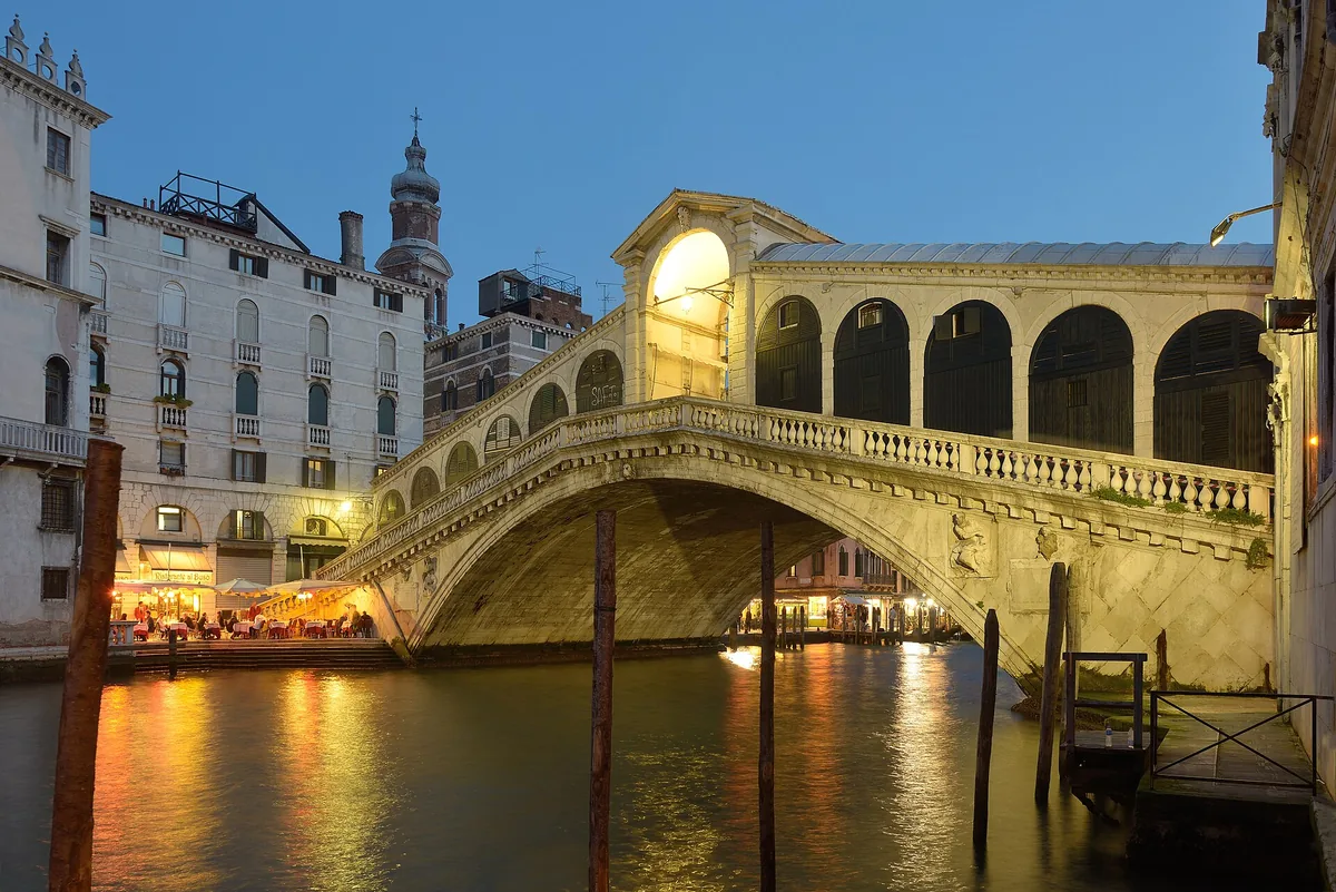 The Rialto Bridge in Venice lit at night over the Grand Canal