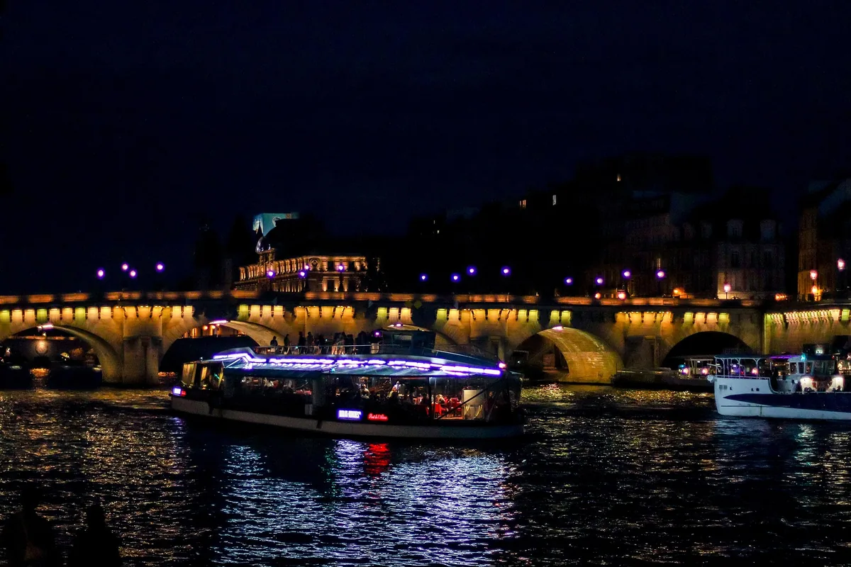 Lit tour boats on the Seine by the Pont Neuf in Paris at night