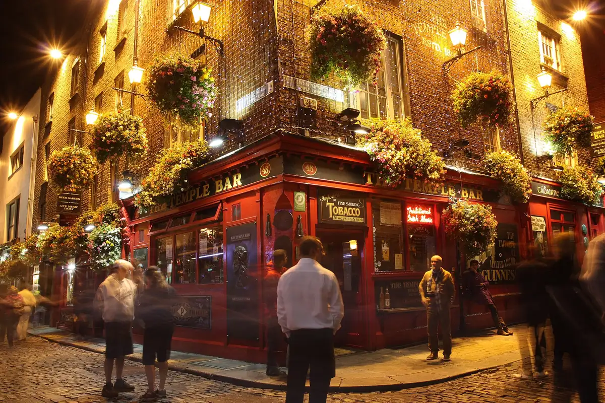 The Temple Bar pub in Dublin at night, its front hung with flowers and lights